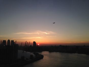 Silhouette buildings in city against sky during sunset