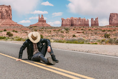 Man sitting on road against mountains