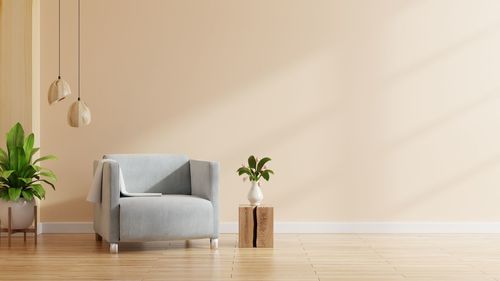 Living room interior wall mockup in warm tones with armchair on cream color wall background.