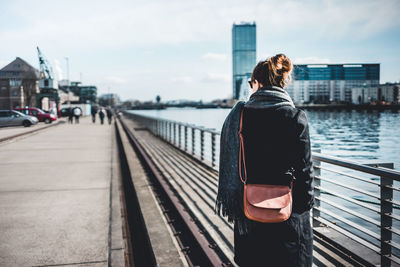 Rear view of woman on bridge over river in city