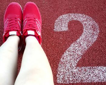 Low section of woman standing on red shoes