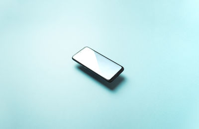 Close-up of mobile phone against blue background