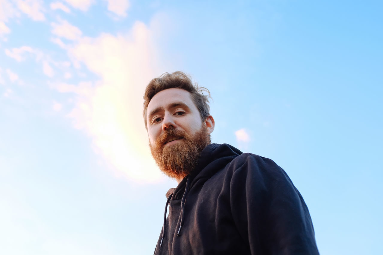 low angle view, beard, sky, real people, day, outdoors, one person, headshot, lifestyles, men, nature, young adult