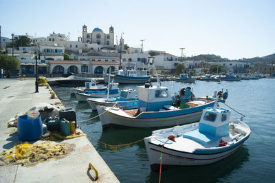 Boats moored at harbor in city against clear sky