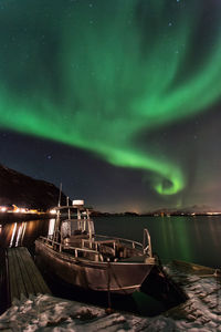Boat moored at illuminated shore against sky