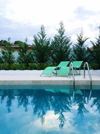 Swimming pool by trees against sky