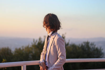 Portrait of young long-haired boy in an elegant blush suit outfit looking sad and heartbroken
