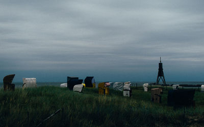 Hooded beach chairs on field against sky