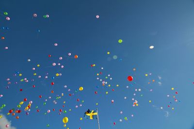 Low angle view of colorful balloons against blue sky