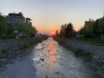 Road amidst buildings against sky during sunset