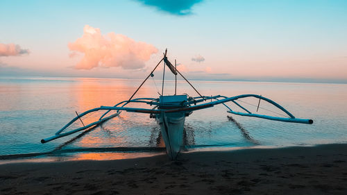 Rowboat moored at shore of beach during sunset