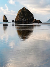 Reflection of rocks in sea against sky