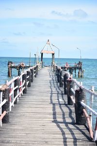 People on pier at beach against sky