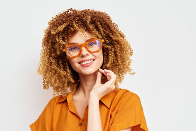 Portrait of young woman wearing sunglasses against white background