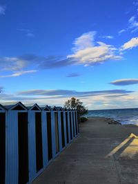 Beach huts by sea against blue sky