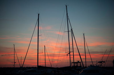 Silhouette sailboats moored at harbor against sky during sunset