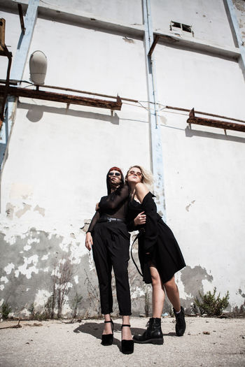 Low angle view of female friends standing against old wall