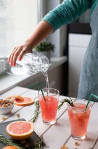 Midsection of woman holding drink on table