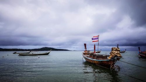 Fisherman boats floating on the sea with thai flag at fisherman village with cloudy sky 