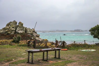Bench on beach by sea against sky