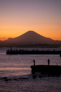 Silhouette pier over sea against sky during sunset