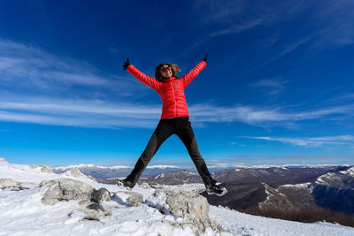 Full length of man with arms raised standing on snow