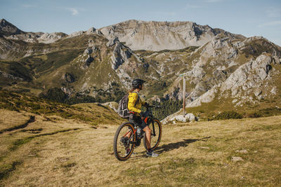 Mid adult woman on electric bicycle admiring view while standing at somiedo natural park, spain