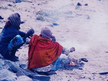 Men sitting by bonfire on field during winter