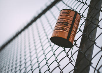 Low angle view of tin can hanging on chainlink fence