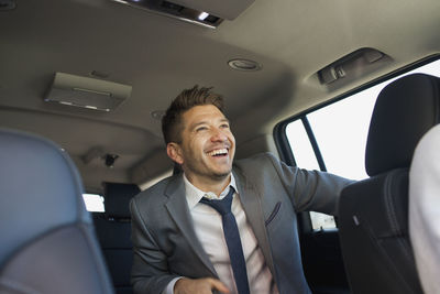 Young business man sitting in car service limousine