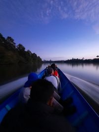 Rear view of people on lake against blue sky