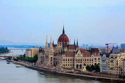 Buildings by river against sky