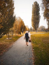 Rear view of woman walking on footpath during autumn