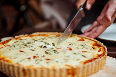 Close-up of hand cutting quiche