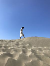 Man standing on sand dune against clear sky