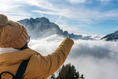 Rear view of female hiker pointing a finger at beautiful snow capped peaks in mountains