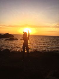 Silhouette man standing on beach against sky during sunset