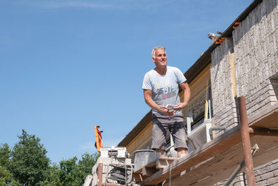 Masonry worker the bricklayer makes the facade of the house from gray bricks