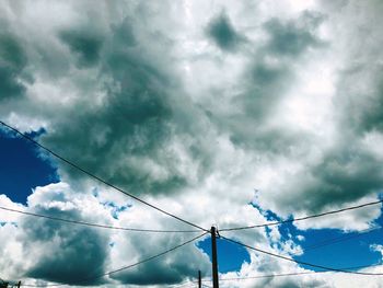 Low angle view of birds flying against cloudy sky