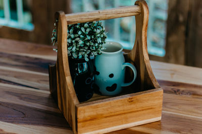 Close-up of plant with container in wooden tray on table