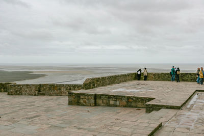 People looking at sea against sky