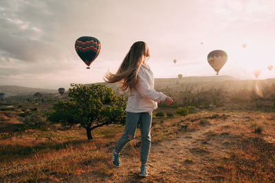 Full length of woman with hot air balloons on field against sky