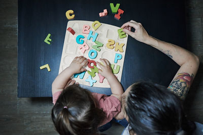 A mother teaching her daughter the letters of the alphabet. concept of learning