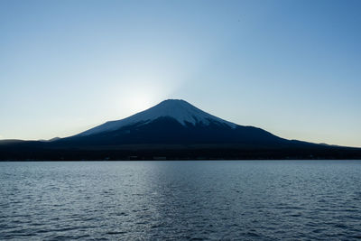 Scenic view of lake and mountains against clear blue sky