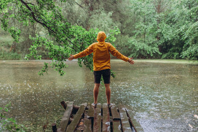 Rear view of girl standing by lake in forest