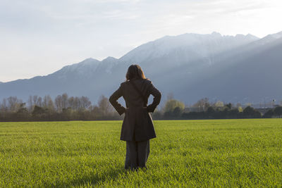 Rear view of woman standing on field against mountains