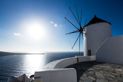 Traditional windmill by sea against sky