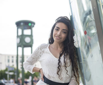 Portrait of smiling young woman standing against white background