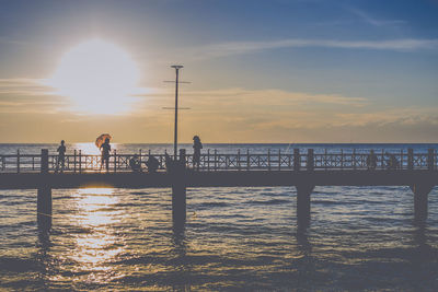 Silhouette man standing by sea against sky during sunset