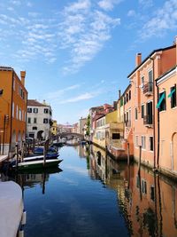 Canal amidst buildings in city against sky